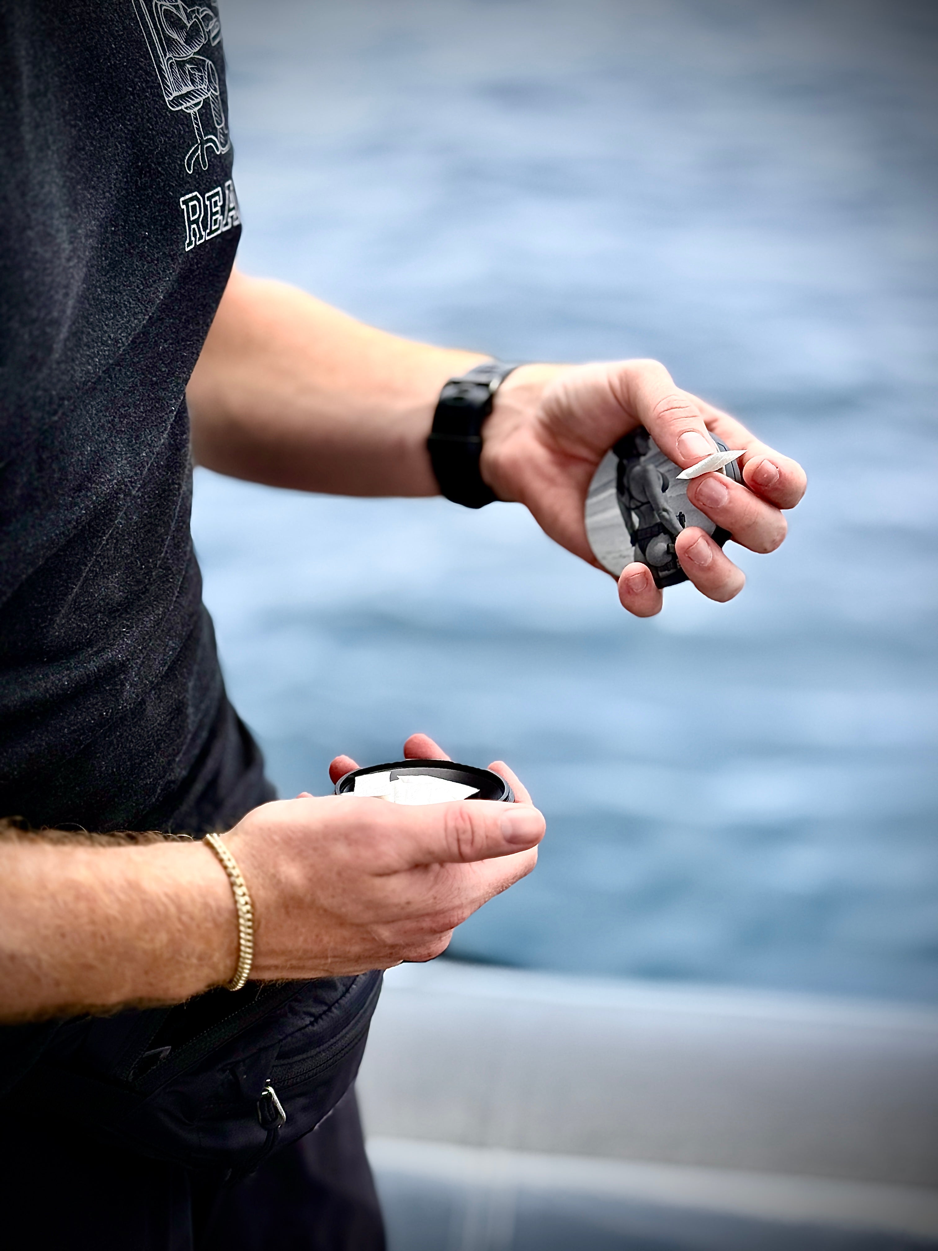 Metal Zyn Can for nicotine pouches with engraved design of "pin-up" style woman in a. bikini and tactical gear. With integrated bottle opener. shown being used by military style man.