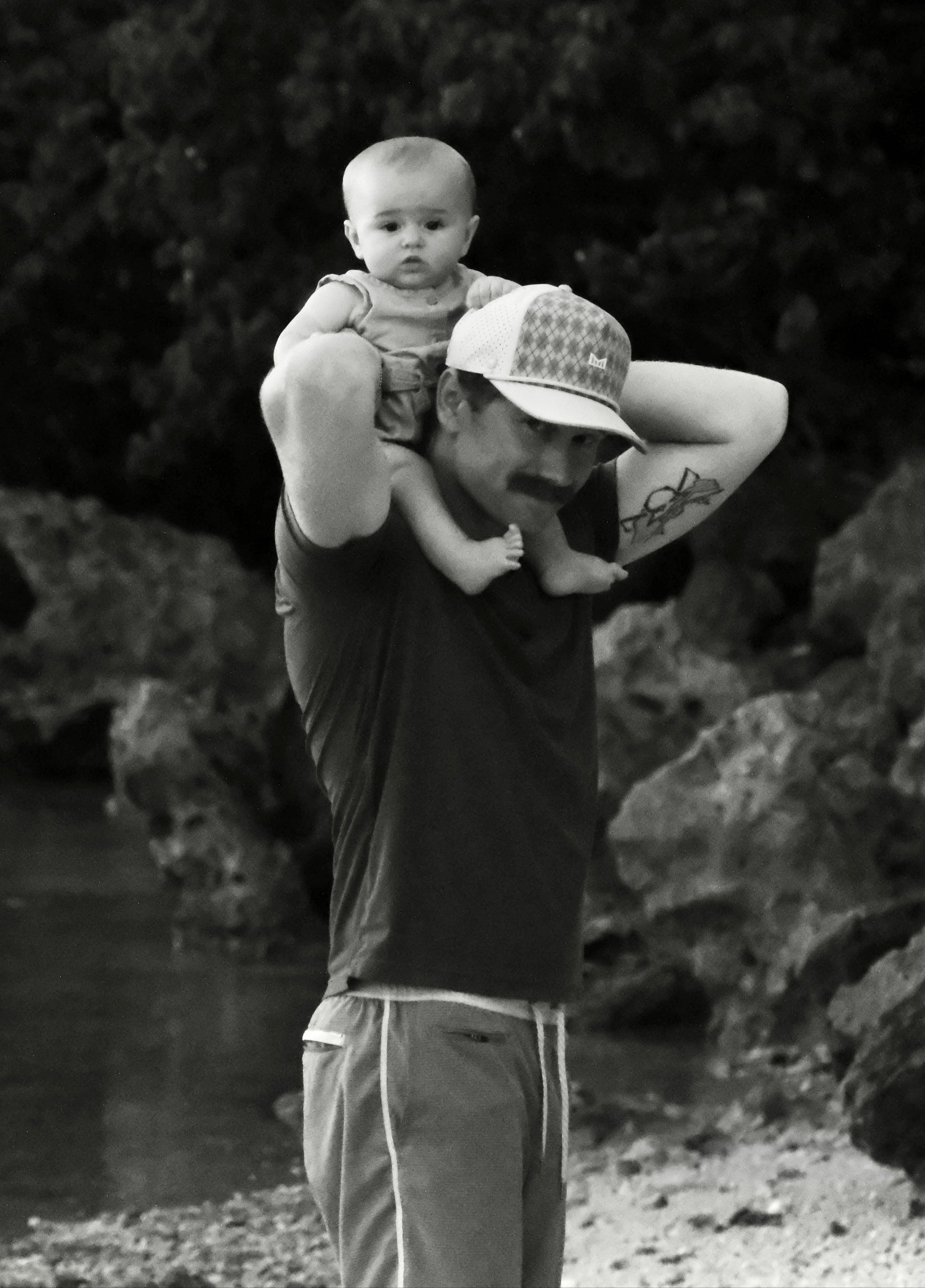 Black and white photo of a man holding a child against a natural background