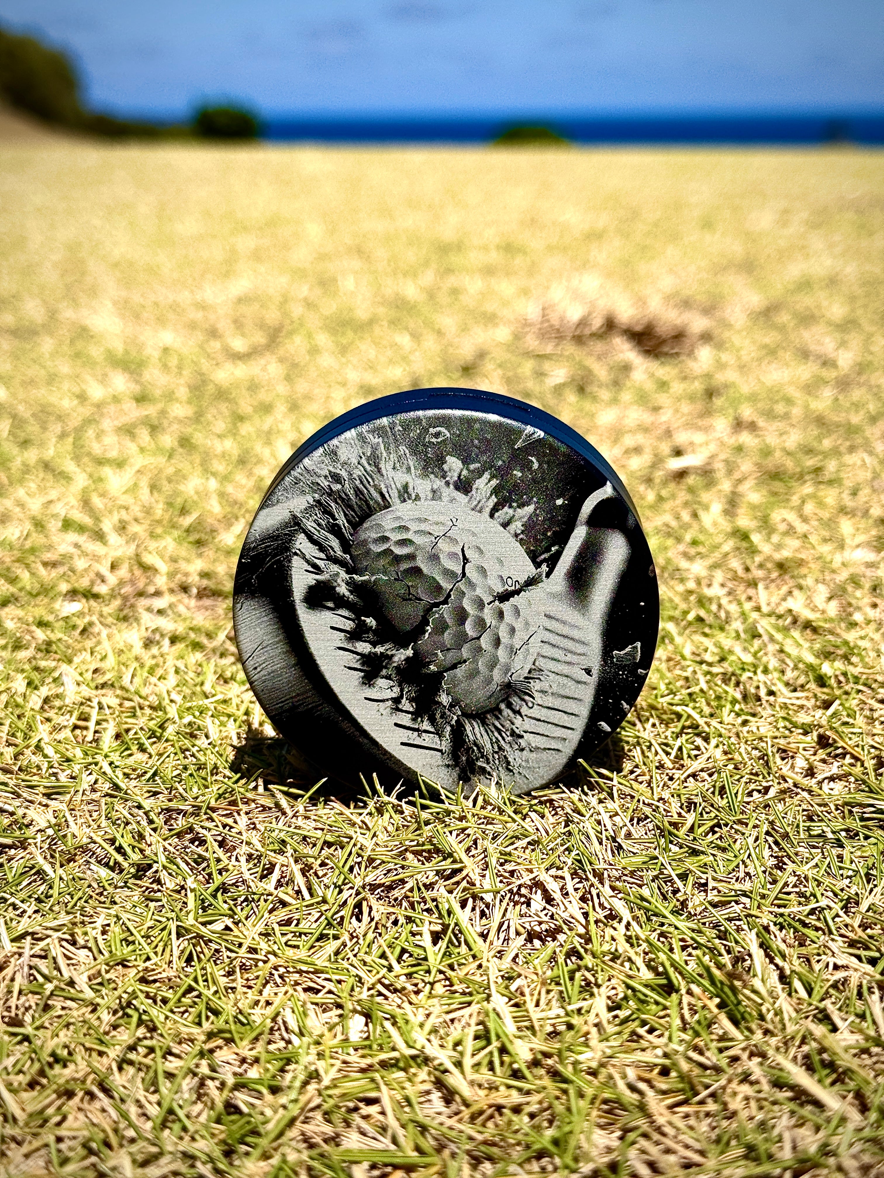 Metal Zyn Can for nicotine pouches with golf club and ball engraved design. With integrated bottle opener. Displayed on a golf green