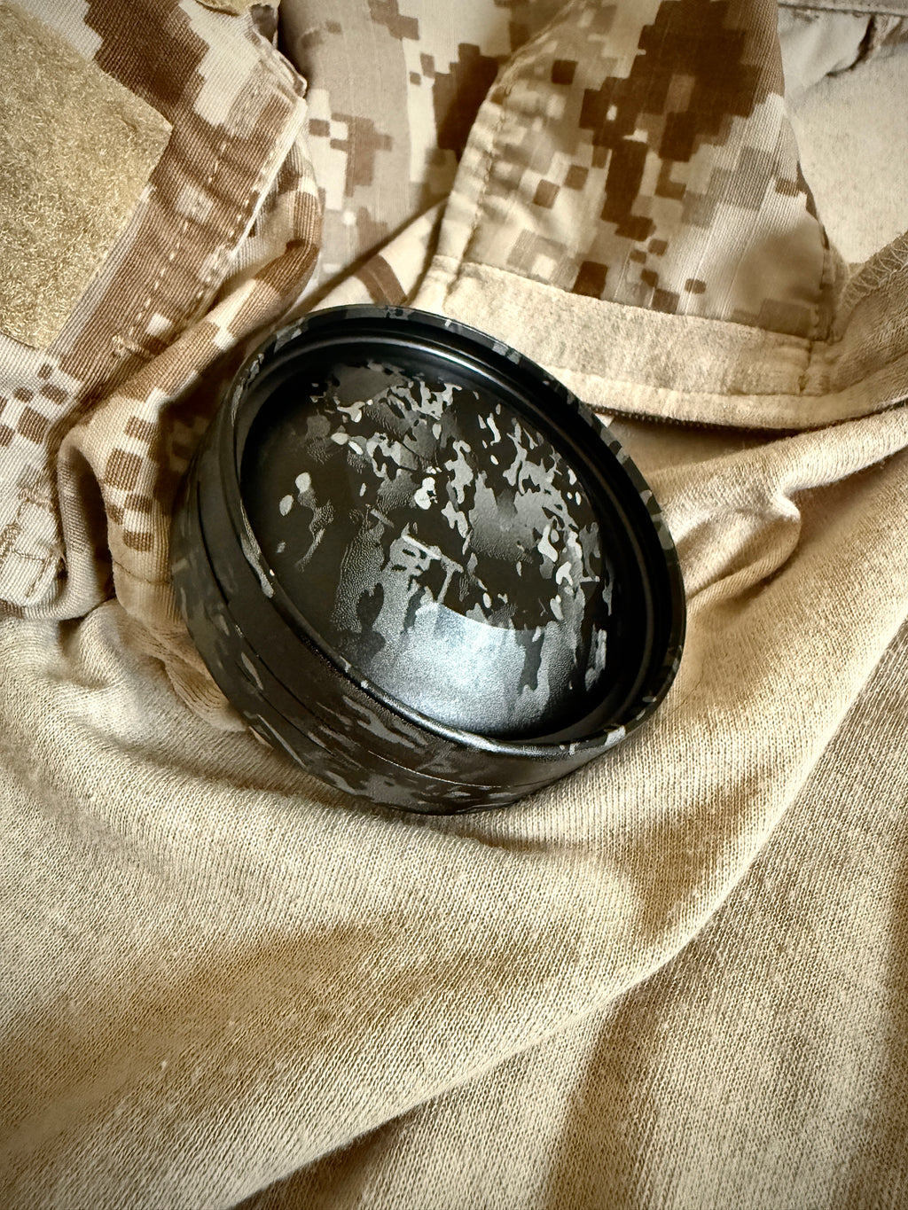 Metal Zyn Can for nicotine pouches completely engraved with camouflage design. With integrated bottle opener. Displayed on crye camouflage uniform.