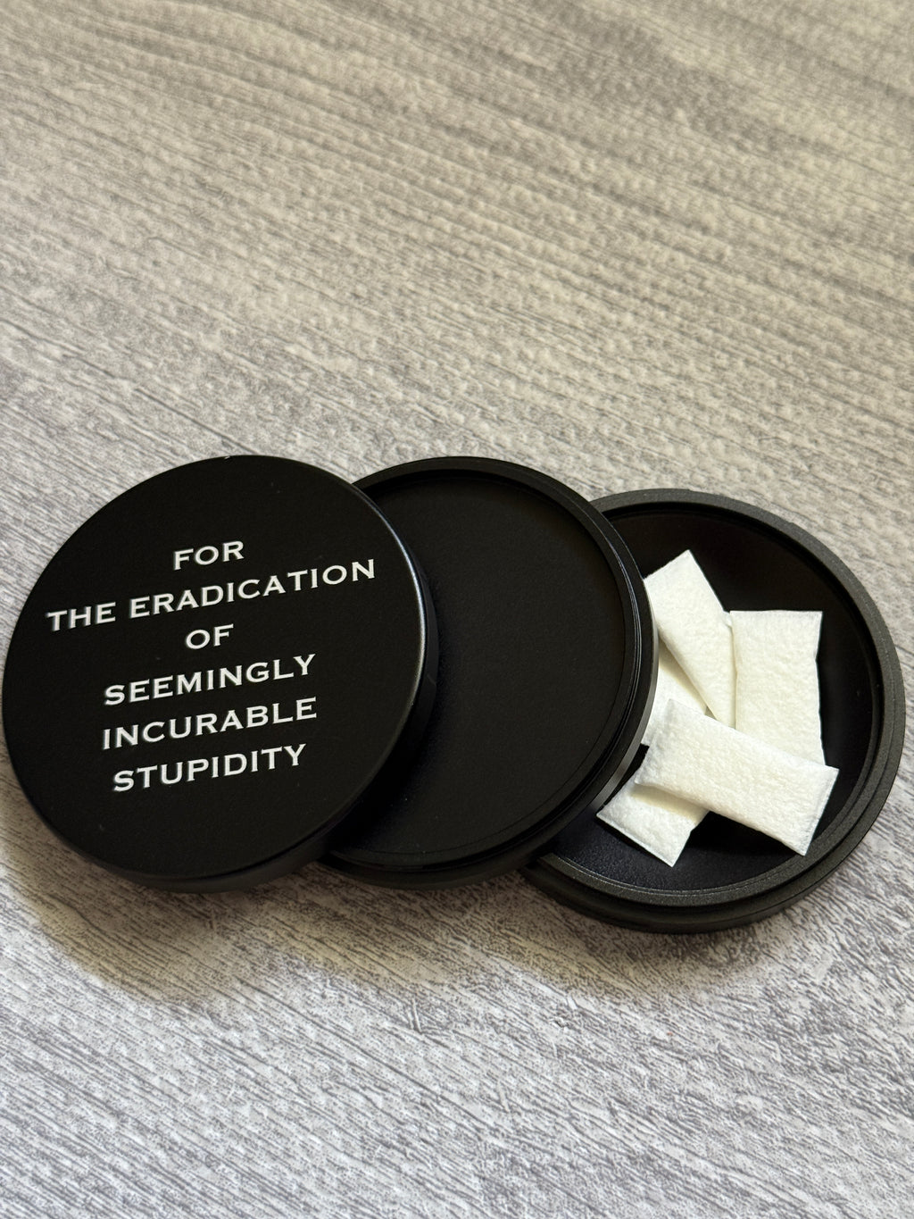 Metal Zyn Can for nicotine pouches with engraved design "for the eradication of seemingly incurable stupidity". With integrated bottle opener. 