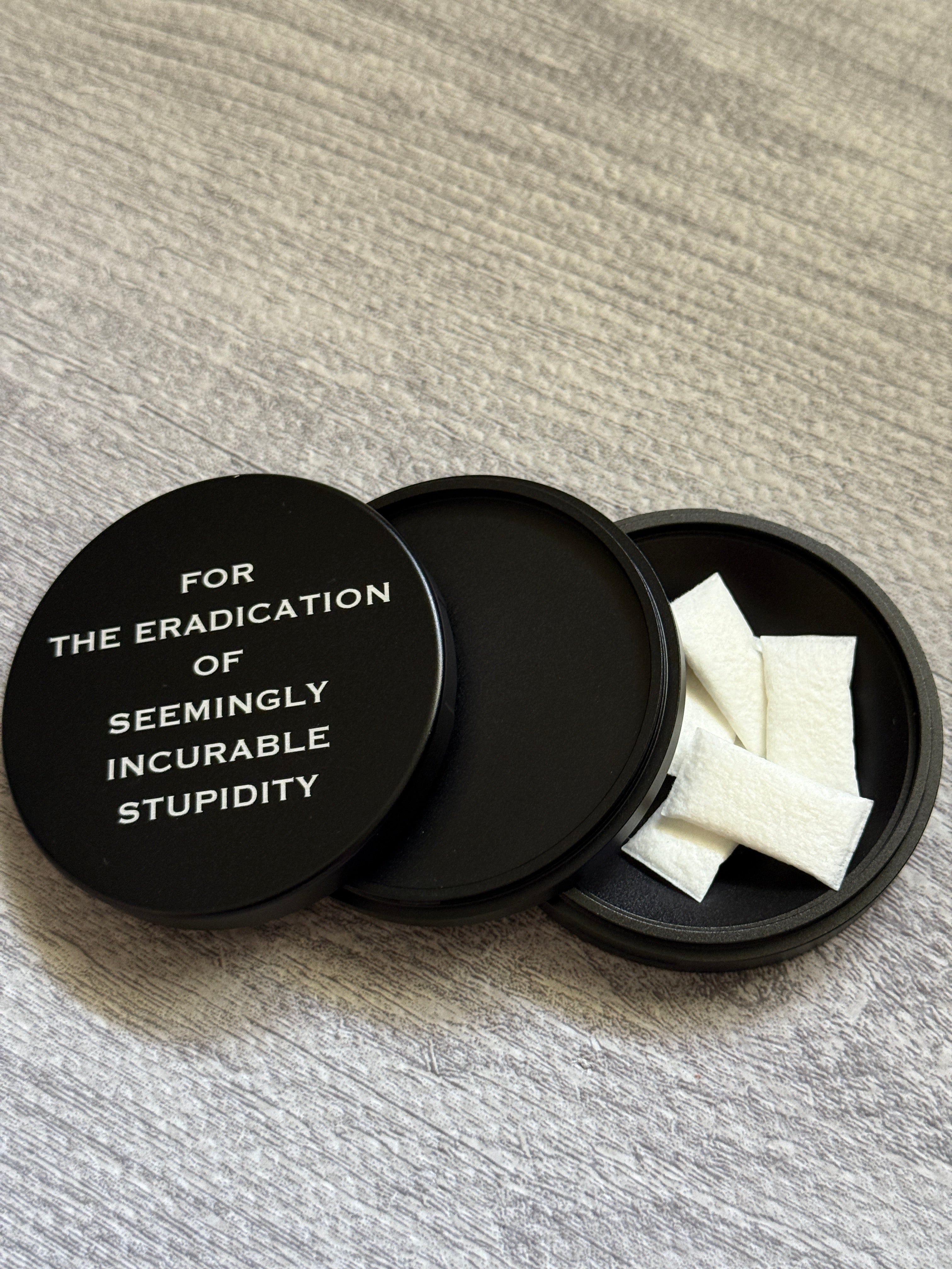 Metal Zyn Can for nicotine pouches with engraved design "for the eradication of seemingly incurable stupidity". With integrated bottle opener. 